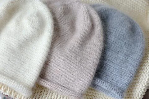 Three hats of the same style in blue, beige and white made of wool on the spokes Stock Photos