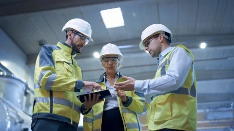 Three Heavy Industry Engineers Stand in Pipe Manufacturing Factory, Use Tablet Stock Footage 114867912