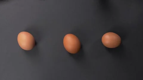 Three hen's eggs in shell rotate on their axis on a dark background. Stock Footage 281660381