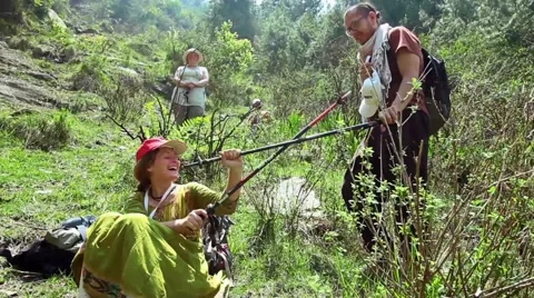 Three hikers-a man and two women-play with their walking sticks in Himalayas Stock Footage 66525287