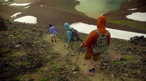 Three hikers walk down big hill Stock Footage 59518981