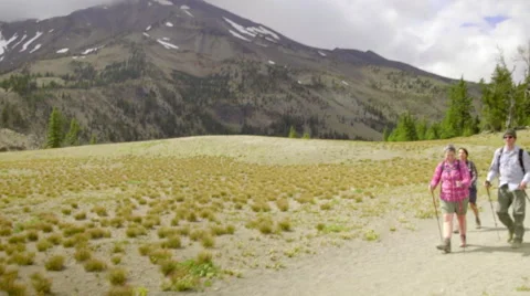 Three hikers walk with a mountain in the background Stock Footage 59082036