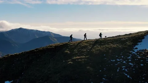 Three hikers walking up a hill before sunset Stock Footage 165074342