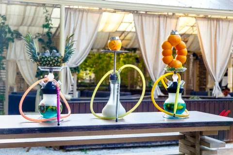 Three hookahs stand on the table in the cafe. Hookah on a pineapple hookah on Stock Photos