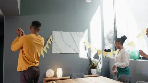 Three hosts arriving with clap, hanging yellow bunting and aligning balloons for Stock Footage 331193446
