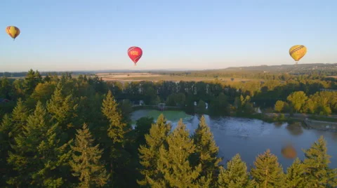 Three hot air balloons float over river Stock Footage 59789113