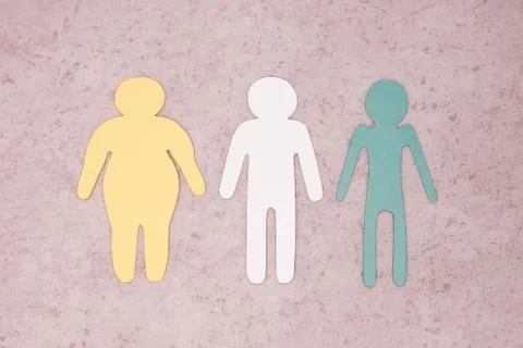 Three human figures are cut out of paper. Overweight, normal build and thinness. Stock Photos