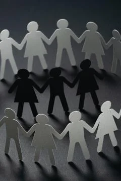 Three human paper figures surrounded by circle of paper people holding hands on Stock Photos