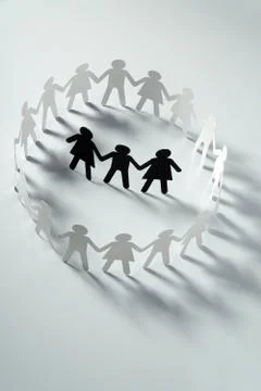 Three human paper figures surrounded by circle of paper people holding hands on Stock Photos