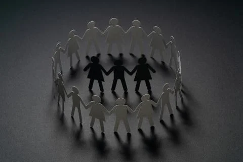 Three human paper figures surrounded by circle of paper people holding hands on Stock Photos