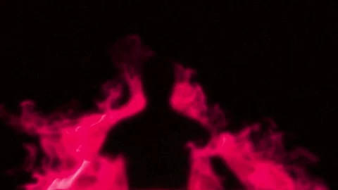 Three human silhouettes surrounded by vibrant pink neon smoke against a pitch 库存影片 345214009