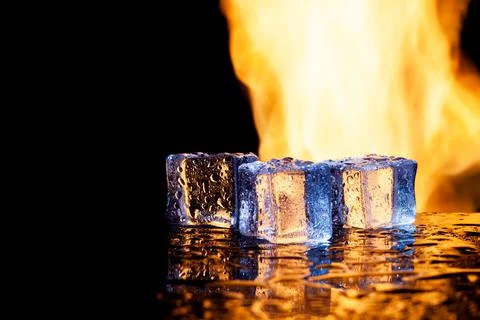 Three ice cubes against the background of fire, concept Stock Photos
