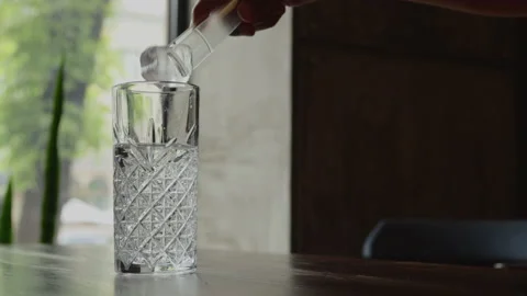 Three ice cubes are placed in a crystal glass with mineral water Stock Footage 156841918