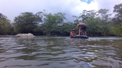 Three indigenous children trying to stand in a floating inner tube in ecuador Stock Footage 113593333