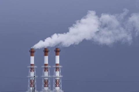Three industrial chimneys release thick white smoke into the blue sky, Photos
