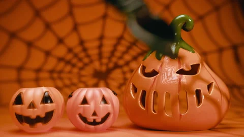 Three jack-o-lantern pumpkins with spiderweb shadow on orange background. Stock Footage 318078824