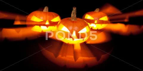 Three jack-o-lantern pumpkins glowing in the dark Stock Photos