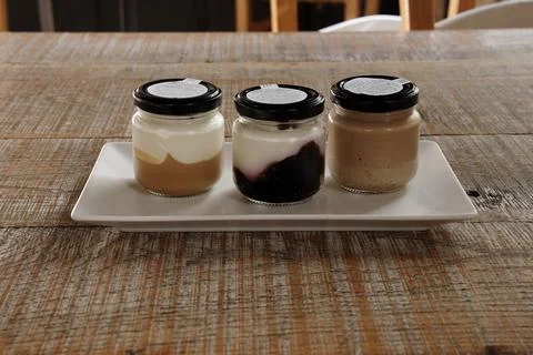 Three jars of different desserts are on a wooden table Stock Photos