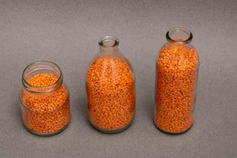 Three jars with orange and red lentil on table, legumes concept, horizontal f Stock Photos