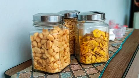 Three jars of snacks consisting of peanuts, banana chips and dry puff pastry Stock Photos