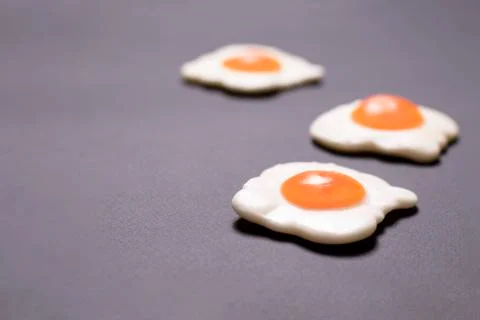 Three jelly in the form of fried eggs lie on the right on a gray background Stock Photos