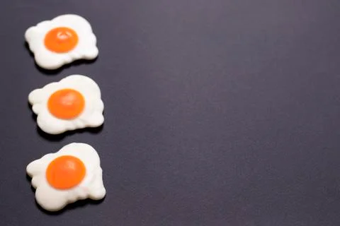 Three jelly-fried eggs lie to the left on a black background Stock Photos