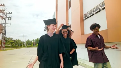 Three joyful young graduates share laughter and excitement after their grads Stock Footage 326727149