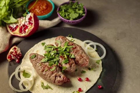 Three kebabs on thin pita bread, with herbs, onions and pomegranate seeds. Spicy Stock Photos