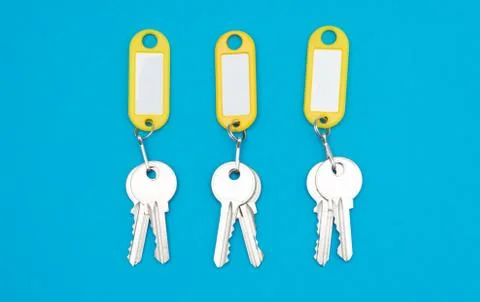 Three keys pair on yellow keychains blue background and copyspace Stock Photos