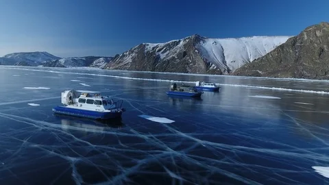 Three Khivus ship boat hover Transparent Ice cracks Lake Baikal Mountains Drone  Stock Footage 87720180