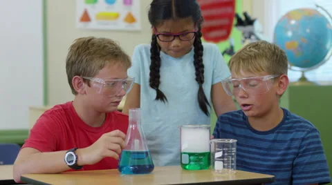 Three kids in classroom looking at science experiment Stock Footage