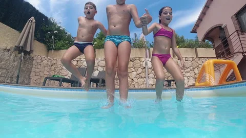 Three kids jumping into a swimming pool Stock Footage 168980997