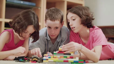Three kids playing with lego bricks at home Stock Footage 95245849