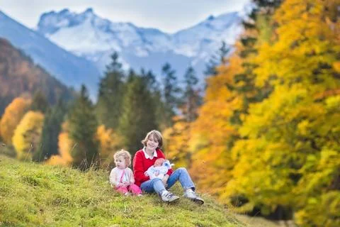 Three kids playing while hiking in beautiful snow covered mountains Stock Photos