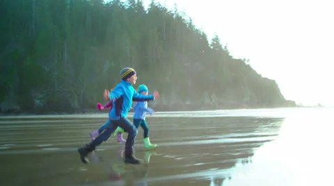 Three kids run down the beach with the camera Stock Footage 33892776