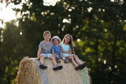 Three kids sitting on a haystack Stock Photos
