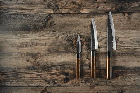 Three kitchen knives arranged on a rustic wooden surface in natural light 库存照片