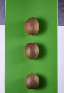 Three kiwis on a green background Stock Photos