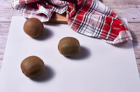 Three kiwis on white background and kitchen towel Stock Photos