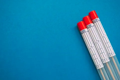 Three laboratory sample tubes with red cap on blue background Stock Photos