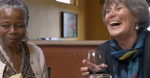 Three ladies over 50 drinking wine and laughing at a get together Stock Footage 81007920