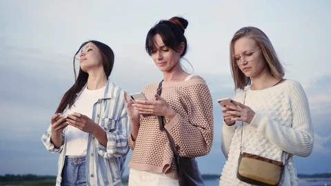Three ladies texting in their smart phones in the street. 스톡 동영상 117847517