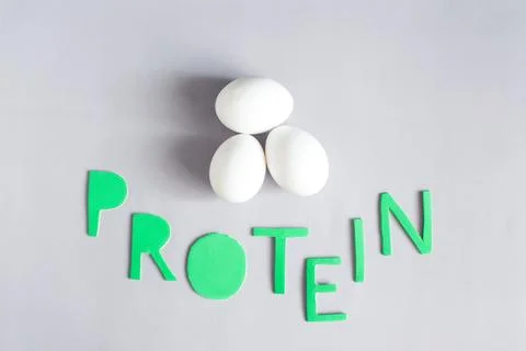 Three large chicken eggs and the inscription in colored letters "protein" Stock Photos