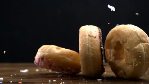 Three large donuts falling down into table surface on black backdrop captur.. Stock Footage 273368766