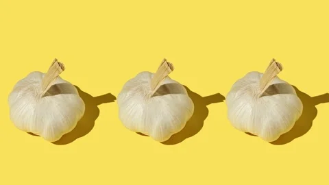 Three large garlic close up on a yellow background Stock Footage 169280489