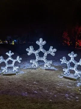 Three Large Glowing Snowflake Light Sculptures in a Winter Night Landscape Stock Photos
