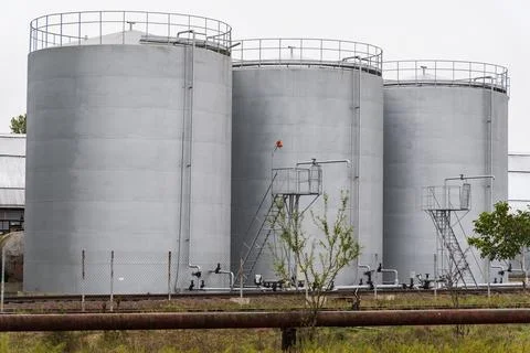 Three large gray storage tanks are positioned closely together at an industrial Stock-Fotos