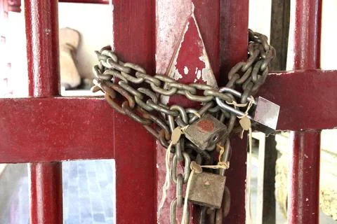 Three large iron chains and padlocks for thick, old, red wooden doors. Stock Photos