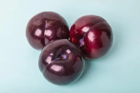 Three large plums on a blue background. Delicious berry for dessert Stock Photos