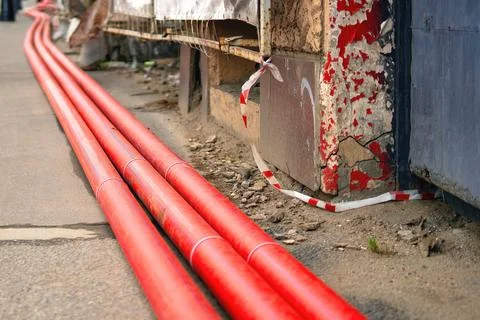 Three large red plastic sewer pipes installed near a building under renovatio Stock Photos